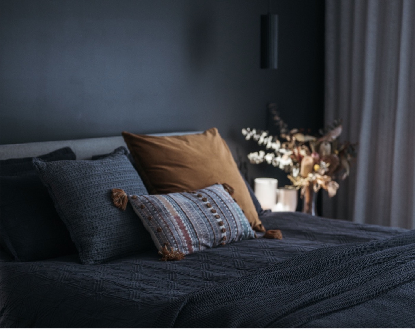 A moody North Street bedroom with navy bedding and a bronze cushion.
