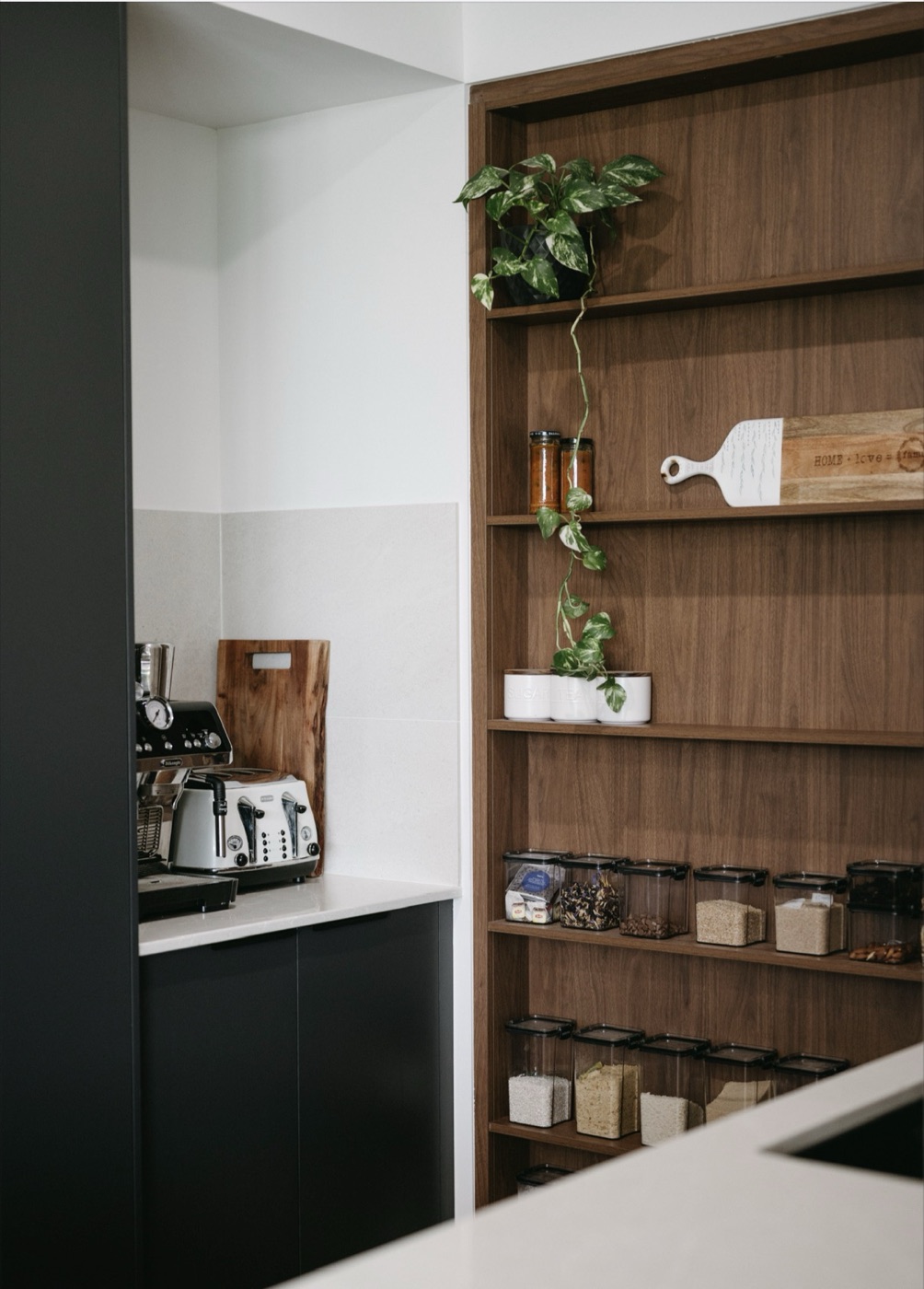 Walnut joinery shelving styled with ceramics and greenery.