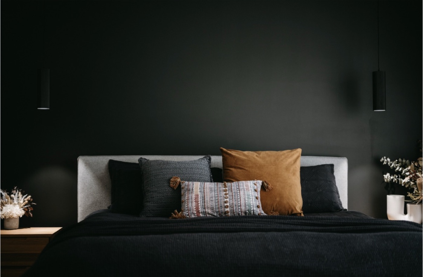 A calm, moody bedroom at North Street — charcoal walls, layered linen and warm light.
