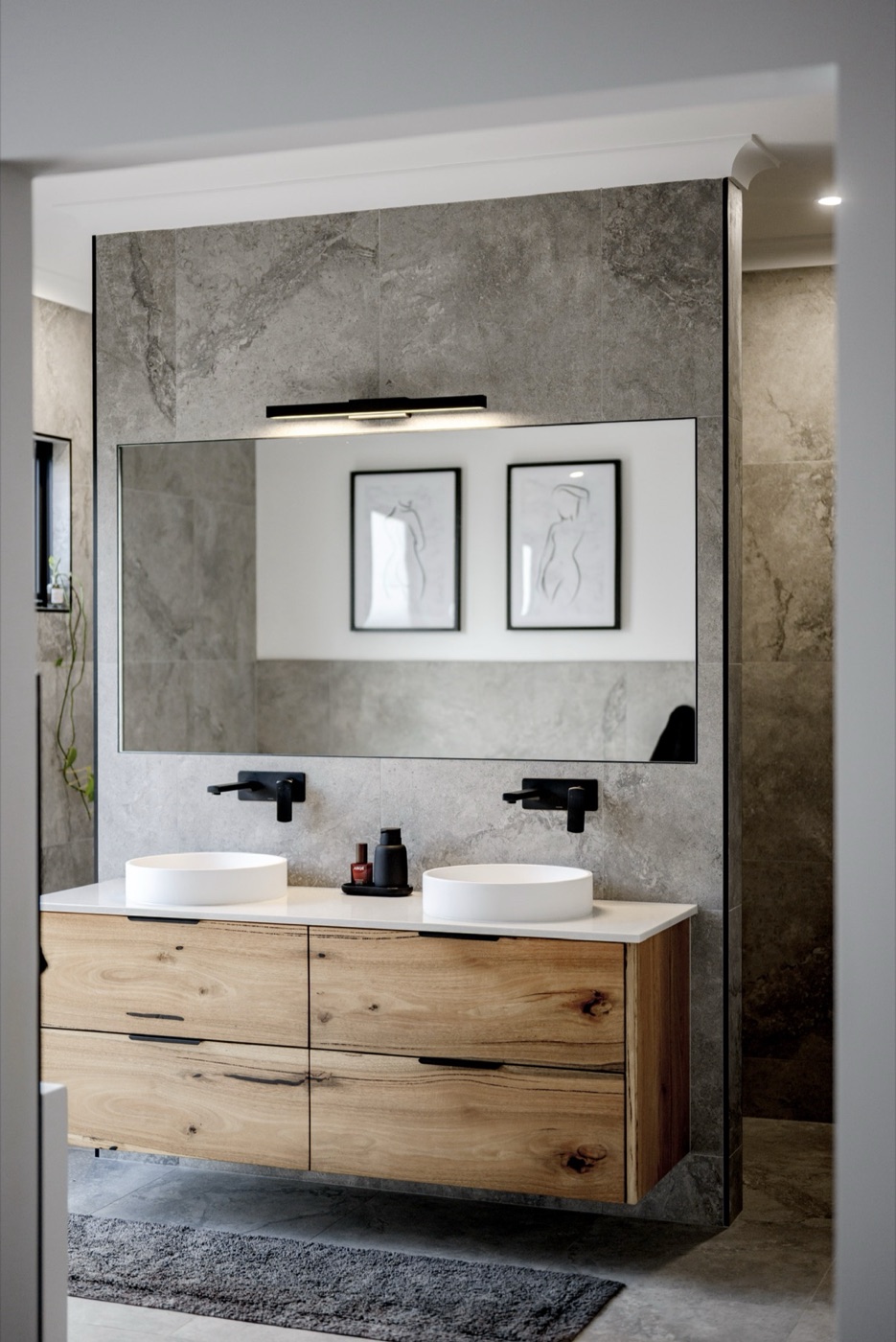 An ensuite with a stone feature wall and oak floating vanity.