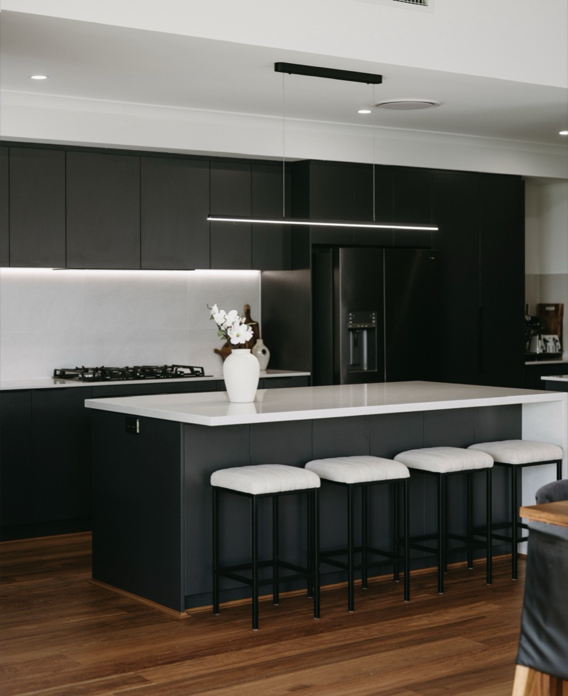 A dramatic black kitchen with a white stone island.